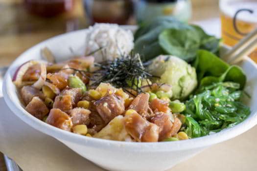 white bowl with tuna salmon shredded nori cucumber edamame roasted corn rice